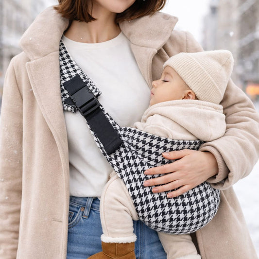 Porte-bébé style sling avec bandoulière, motif pied-de-poule noir et blanc. Bébé apaisé contre sa mère. Position physiologique et ergonomique