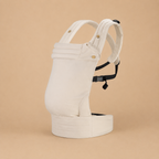 Porte-bébé kangourou physiologique beige présenté, vue de côté, bretelles rembourrées, appui tête, soutien abdo sur fond beige