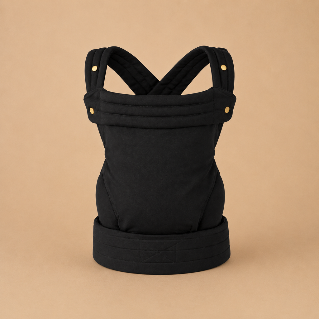 Porte-bébé kangourou physiologique et  noir présenté, vue de face, bretelles rembourrées, sangle ajustable sur fond beige