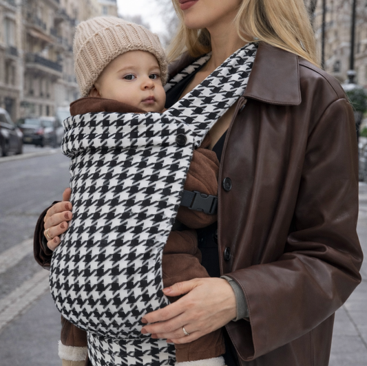 Porte-bébé kangourou physiologique pied-de-poule noir blanc, maman blonde bébé assis confortablement, bretelles soutien épaules