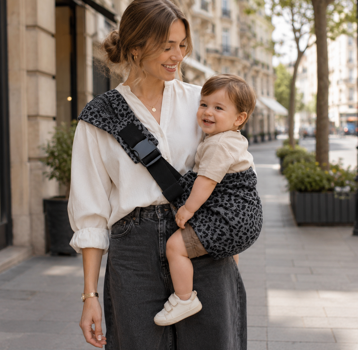 maman brune qui porte son bébé lors d'une balade de printemps avec un sling leopard anthracite