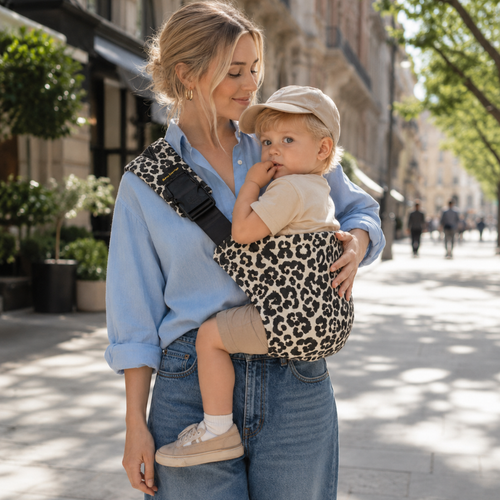 Maman blonde se promène avec son bébé blond. Il était fatigué, elle l'a donc mis dans le sling brushhoo coloris léapard ecru