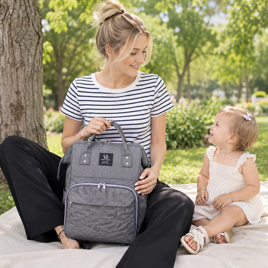 maman qui se repose dans un parc avec sa fille. Elle a emporté son sac à langer avec l'essentiel bébé