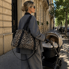 Maman blonde qui se balade avec sa poussette et son sac à langer léopard. Elle a dans son sac l'essentiel de bébé pour la journée