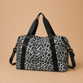 Sac à langer bébé coloris léopard sur fond  beige, vue de face. Pratique, confortable et stylé pour le quotidien. Motif léopard blanc. Il a une contenance de 23L.