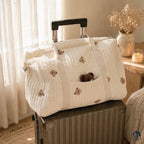 Sac à langer bébé brodé matelassé Brushhoo motif ourson posé et accroché sur une valise
