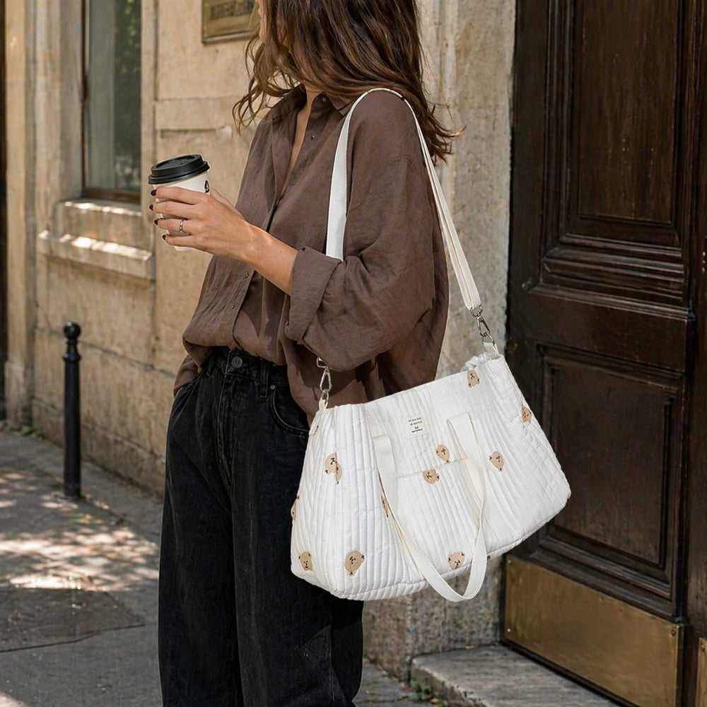 Maman brune qui se balade avec son café et son sac à langer avec l'essentiel bébé