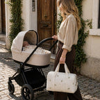 Maman blonde qui se balade avec son bébé dans la poussette et son sac à langer avec l'essentiel bébé