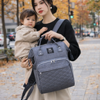 maman avec son bébé à la main et son sac à dos à langer gris pratique
