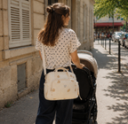 Maman brune qui se balade avec son sac à langer motif ourson dans la rue en train de pousser sa poussette
