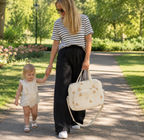 Maman blonde qui se balade avec son sac à langer motif ourson au parc avec sa petite fille